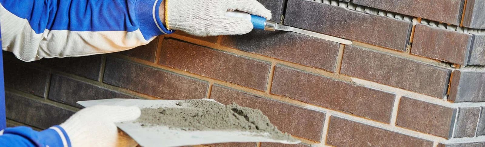 Bricklayer pointing brick wall with trowel