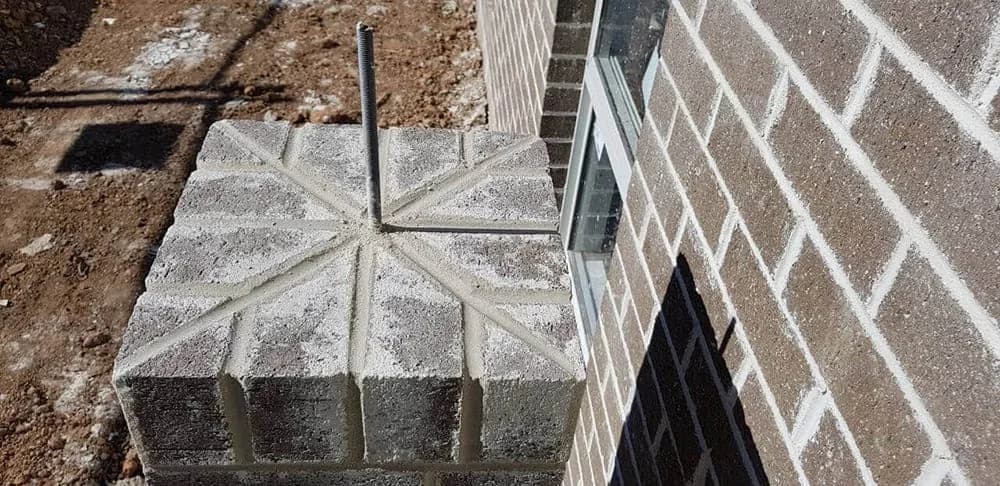 Concrete block pier beside brick wall