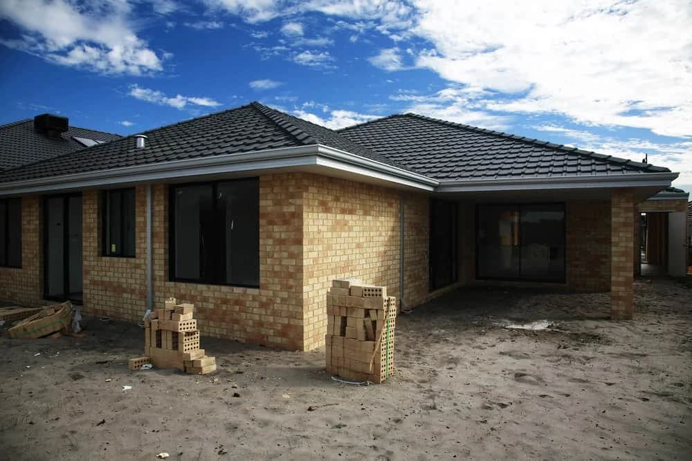 Tan brick home construction dark roof