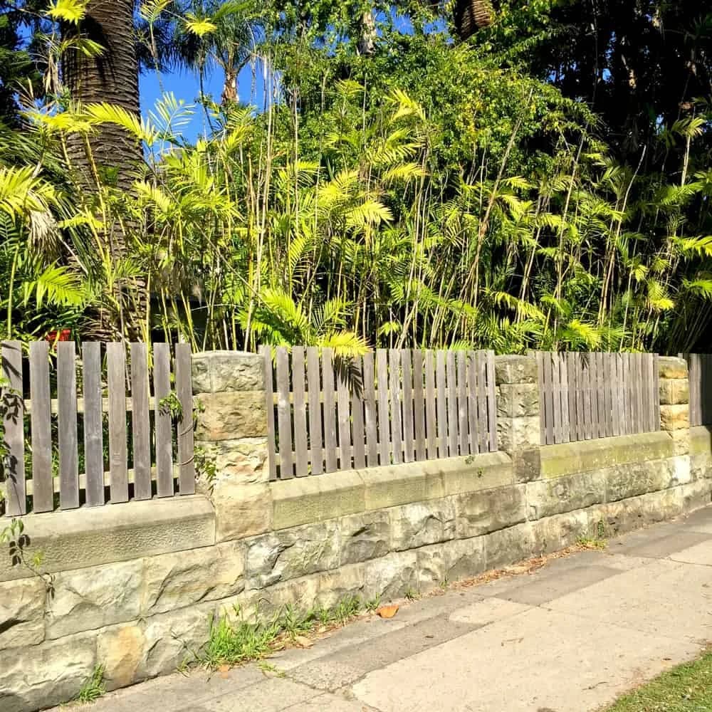Stone retaining wall and timber fence beside garden planting